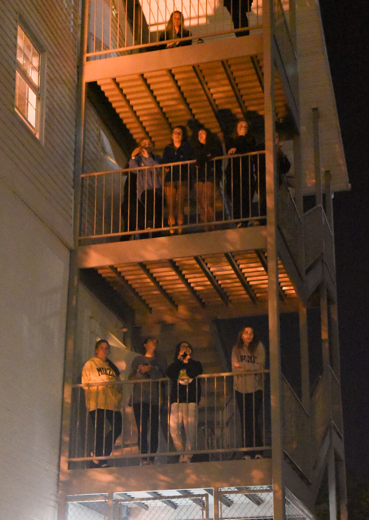 Students from the Phi Mu fire escape watch others protest outside Phi Gamma Delta